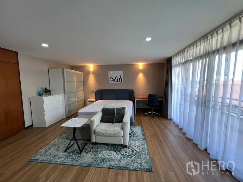 ทาวน์เฮาส์ ให้เช่าหรือขายในSuan Luang, Bangkok - ห้องนอนมุมกว้างผนังกระจกสูงจรดเพดาน ผ้าม่านบาง โซฟาและโต๊ะทำงาน