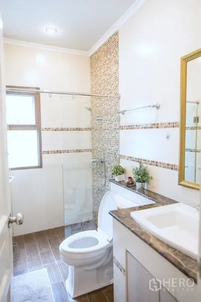 บ้าน ขายในLat Krabang, Bangkok - ห้องน้ำกะทัดรัด มีฉากกั้นอาบน้ำกระจก อ่างล้างหน้า และหน้าต่าง โทนกระเบื้องอุ่น