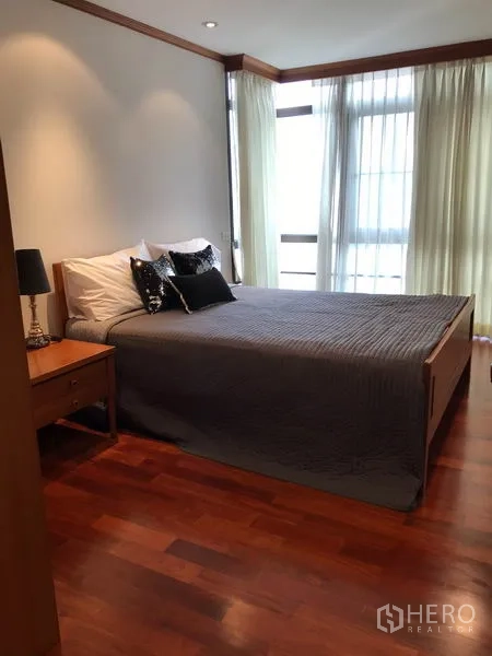 Condominium for rent in Watthana, Bangkok - Bright second bedroom with queen bed, corner windows and sheer curtains on wood flooring.