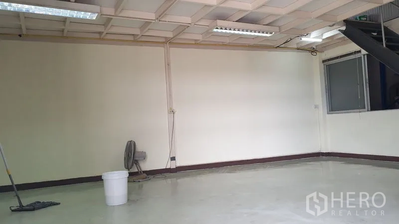Warehouse for rent in Suan Luang, Bangkok - Clean open office or workspace with white walls, fluorescent lights and a window.