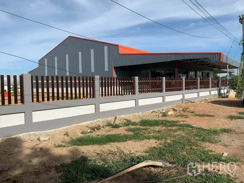Warehouse for sale in Phra Nakhon Si Ayutthaya - Side exterior of the warehouse behind a fence, showing long covered platform and metal cladding.