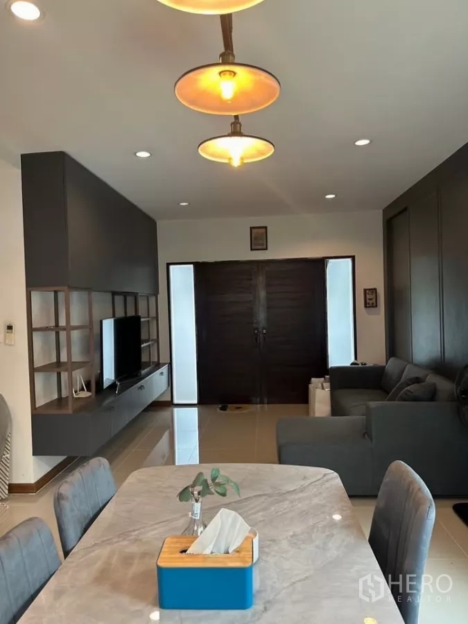 บ้าน ให้เช่าในSuan Luang, Bangkok - พื้นที่รับแขกและรับประทานอาหารแบบเปิดโล่ง โคมไฟแขวน โต๊ะหินอ่อน ชุดชั้นวางทีวี และประตูไม้บานคู่.