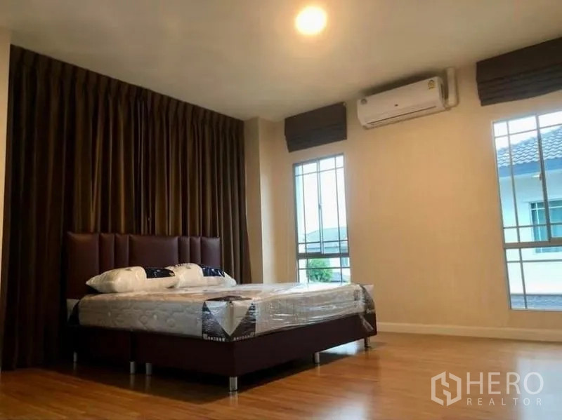 Detached House for rent in Prawet, Bangkok - Spacious master bedroom with king bed, air-conditioning and tall windows.