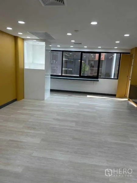 สำนักงาน ให้เช่าในKhlong Toei, Bangkok - โซนทำงานแบบเปิดโล่ง ผนังสีเหลือง หน้าต่างบานกว้าง และพื้นลายไม้