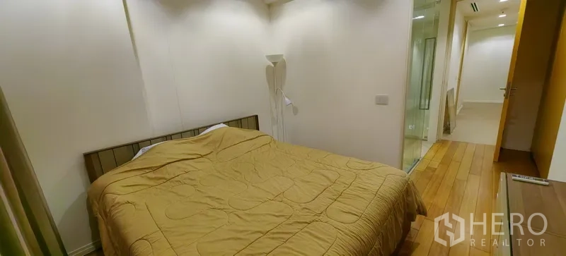 คอนโด ให้เช่าในKhlong San, Bangkok - ห้องนอนพร้อมเตียงคู่ โคมไฟยืน และมุมมองไปยังโถงและห้องอาบน้ำกระจก