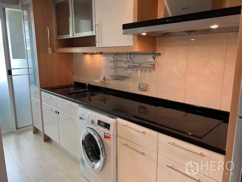 公寓 出租或出售在Watthana, Bangkok - 厨房操作台含水槽、电磁炉、洗衣机，旁有推拉玻璃门