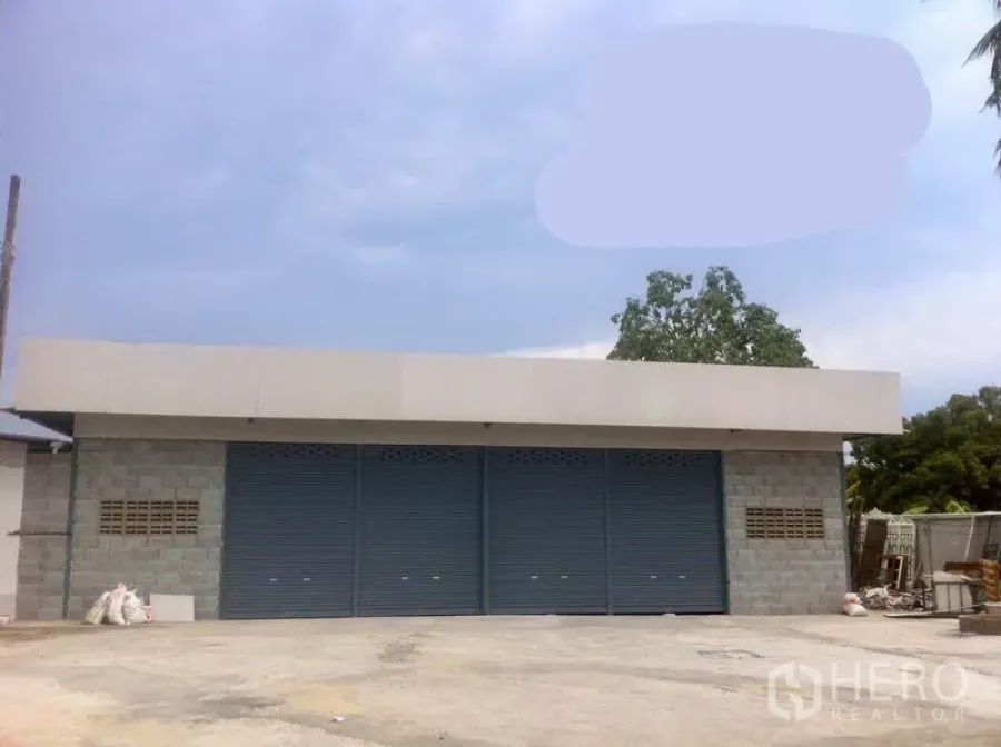 Warehouse for rent in Lam Luk Ka, Pathum Thani - Single-storey warehouse facade with three blue rolling shutters and a wide concrete forecourt in Lam Luk Ka.