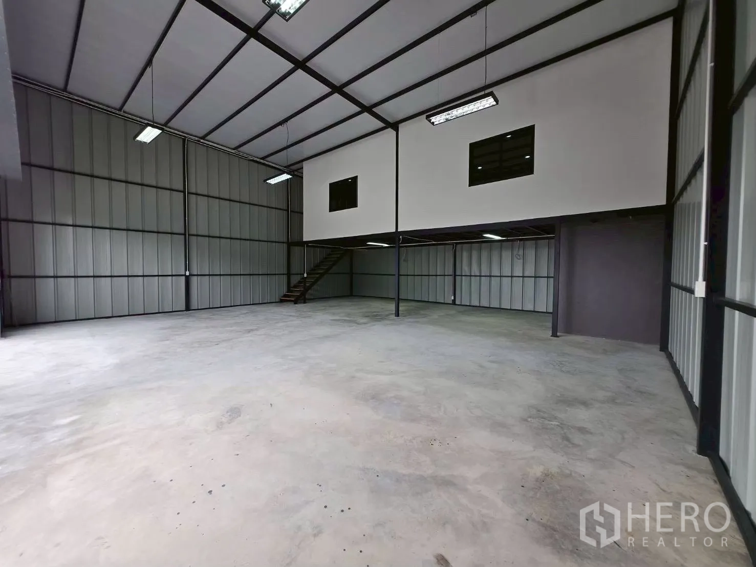 Warehouse for rent in Suan Luang, Bangkok - Spacious high‑ceiling warehouse interior with steel framing, polished floor, and mezzanine office with stairs.