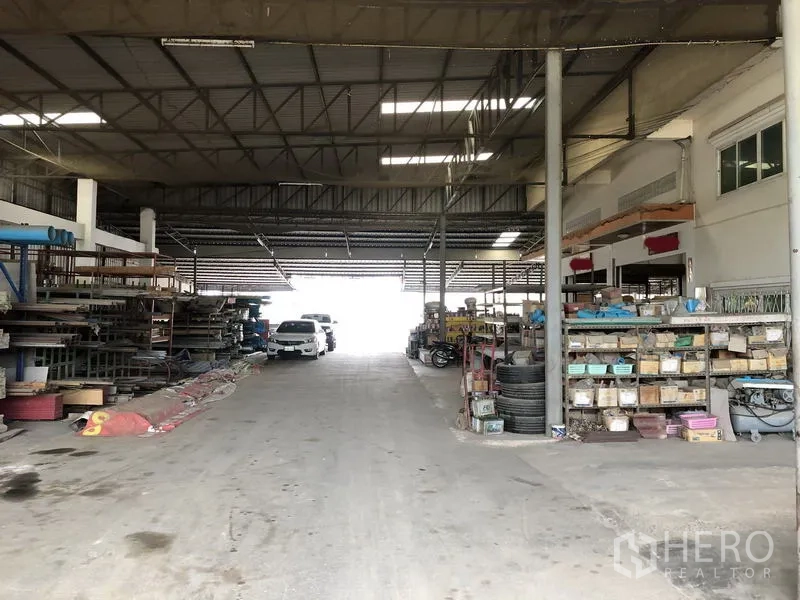 คลังสินค้า ให้เช่าในSai Noi, Nonthaburi - ทางสัญจรกลางแบบไดร์ฟทรู มีรถและชั้นวาง ภายใต้หลังคาเหล็กสูงมีช่องแสง