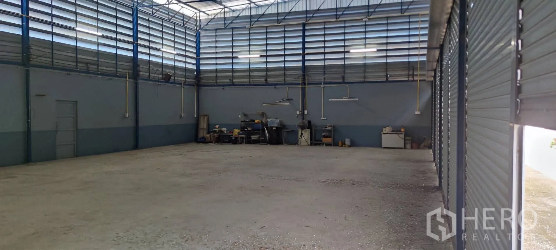 Warehouse for sale in Thung Khru, Bangkok - High-roof warehouse interior with louvered vents and multiple roller shutters.