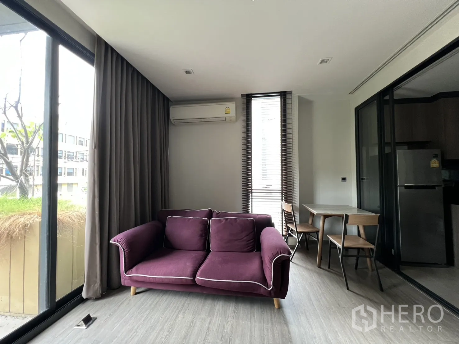 Condominium for rent in Watthana, Bangkok - Bright living room with a purple sofa, dining table, and floor-to-ceiling windows.
