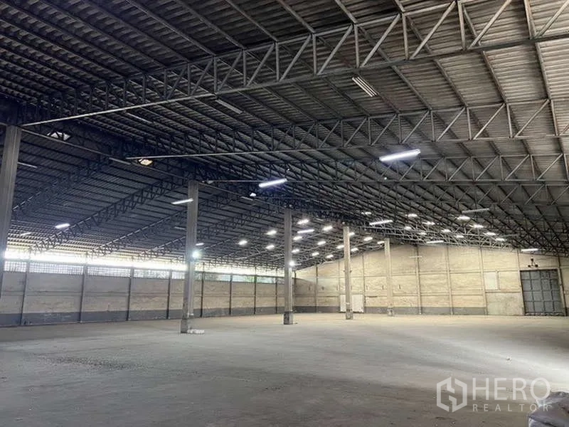 Warehouse for rent - Clear-span warehouse with trussed metal ceiling, skylights and large roller doors.