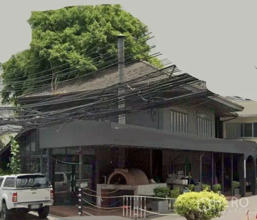 零售空间 出租在Watthana, Bangkok - 曼谷瓦塔那区两层转角商铺，整面玻璃立面，带遮棚前廊与户外砖炉设施。