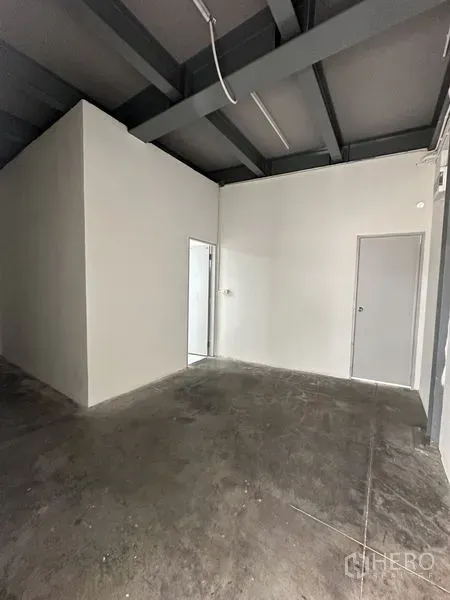 Office Space for rent in Khlong Toei, Bangkok - Open office zone with two internal doors, concrete flooring and industrial ceiling lighting.