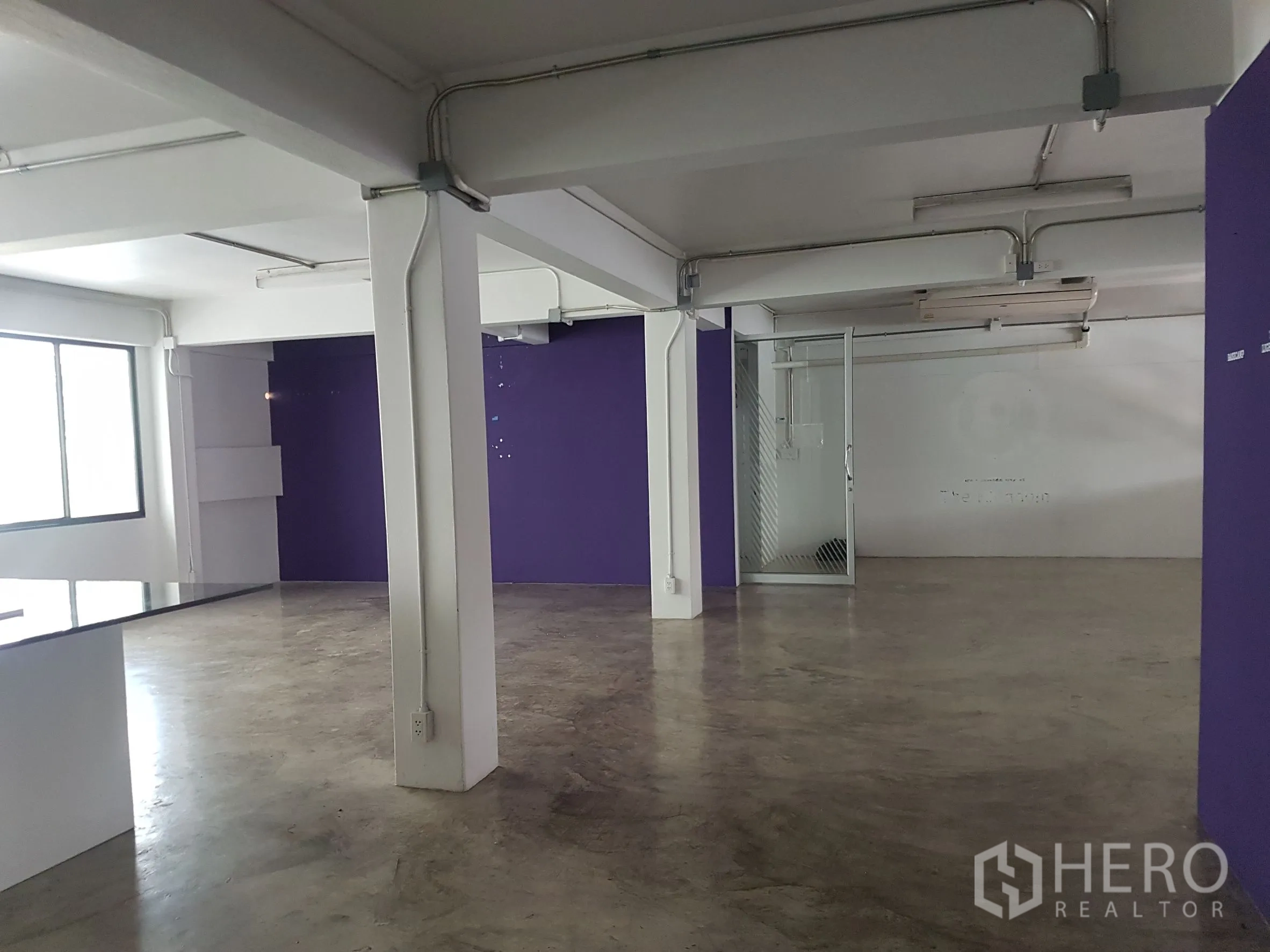 สำนักงานที่บ้าน ขายในKhlong Toei, Bangkok - พื้นที่โล่งพร้อมผนังสีม่วง ประตูกระจก และท่อเดินลอย