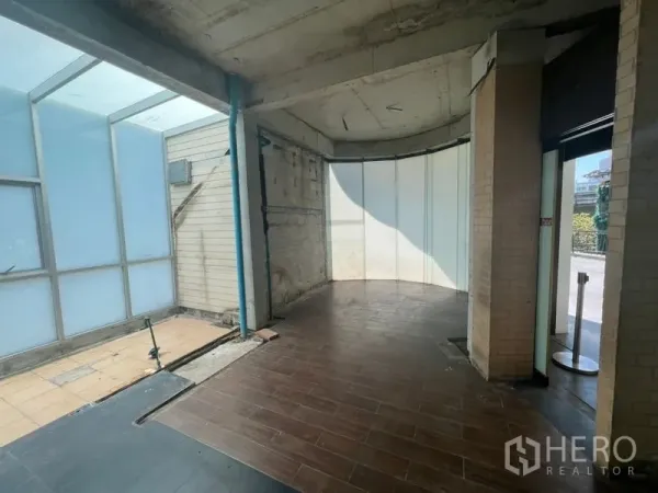 零售空间 出租在Watthana, Bangkok - 入口区展示砖立柱、木纹地砖与侧面玻璃采光。