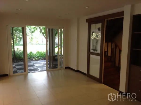 Detached House for rent in Ratchathewi, Bangkok - Bright living area with sliding glass doors opening to a garden patio and a wooden stairway.