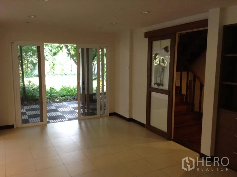 Detached House for rent in Ratchathewi, Bangkok - Bright living area with sliding glass doors opening to a garden patio and a wooden stairway.