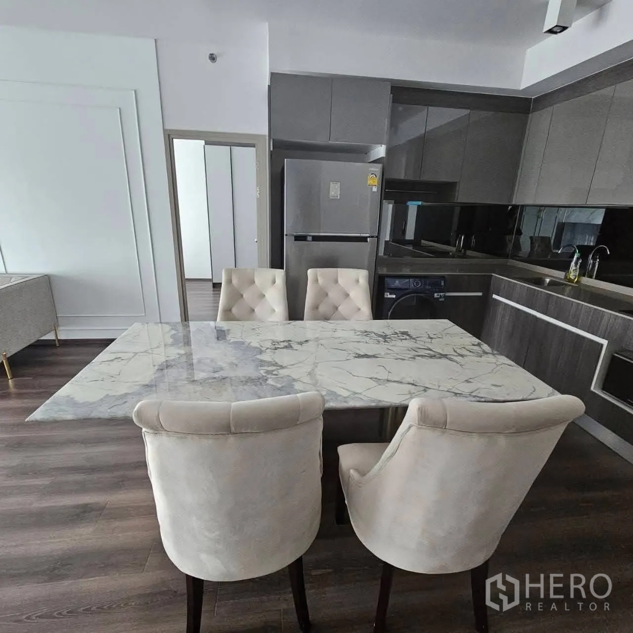 公寓 for rent in Huai Khwang, Bangkok - 开放式厨房餐区，带大理石餐桌、软垫椅、冰箱与橱柜。