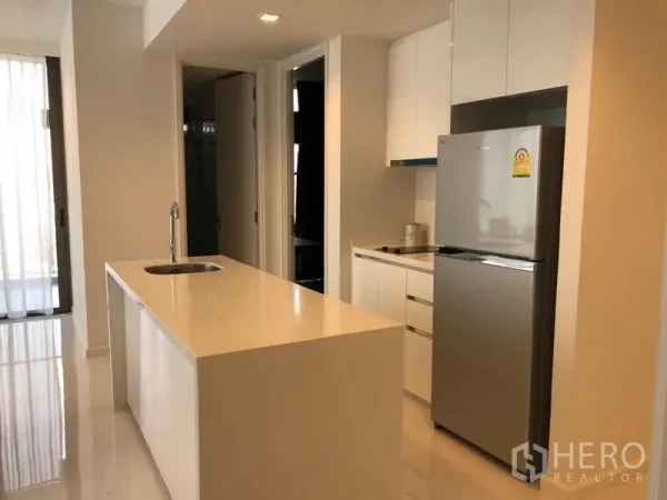 Condominium for rent in Sathon, Bangkok - Sleek galley kitchen featuring a stone island, stainless refrigerator and access to hallway doors.