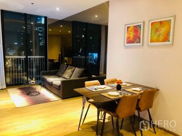 คอนโด ให้เช่าในKhlong Toei, Bangkok - พื้นที่นั่งเล่นและรับประทานอาหารแบบโอเพนพร้อมพื้นไม้ โซฟา ชุดโต๊ะทานข้าว และกระจกเต็มบานมองเห็นวิวกรุงเทพฯยามค่ำคืน