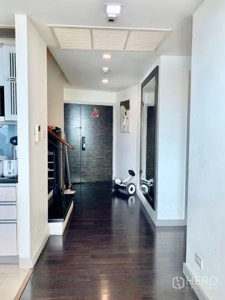 公寓 出租在Khlong San, Bangkok - 明亮玄关走廊，深色木地板与通顶大镜，通往入户门。