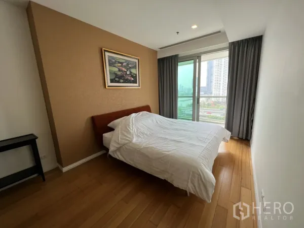 Condominium for rent or sale in Khlong San, Bangkok - Cozy bedroom with wood flooring, bed, accent wall, and sliding glass door to a city view.