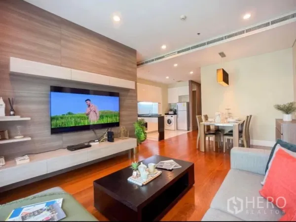 คอนโด ให้เช่าในKhlong Toei, Bangkok - ห้องนั่งเล่นแบบโอเพนแปลน พื้นไม้ ผนังทีวีลอย เห็นมุมทานอาหารและครัวทันสมัย