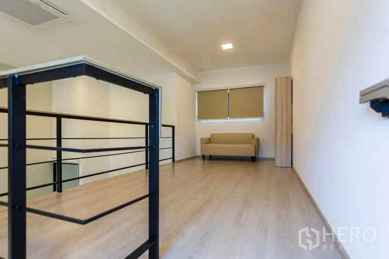 Townhouse for rent in Bang Phli, Samut Prakan - Mezzanine loft area with metal railing, wood flooring and a small sofa.