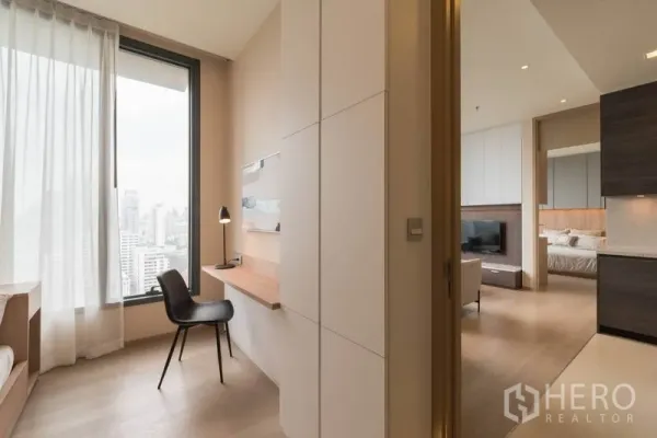 Condominium for rent in Watthana, Bangkok - Compact study nook with built-in desk by a picture window, leading toward the bedroom and living area.