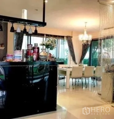 Detached House for sale in Khan Na Yao, Bangkok - Open-plan dining area with chandelier, glossy black kitchen island, and floor-to-ceiling windows.