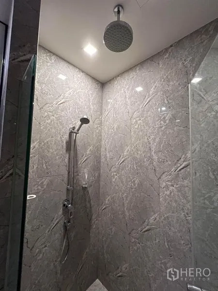 Condominium for rent in Watthana, Bangkok - Marble-tiled shower with rainfall head and glass enclosure.