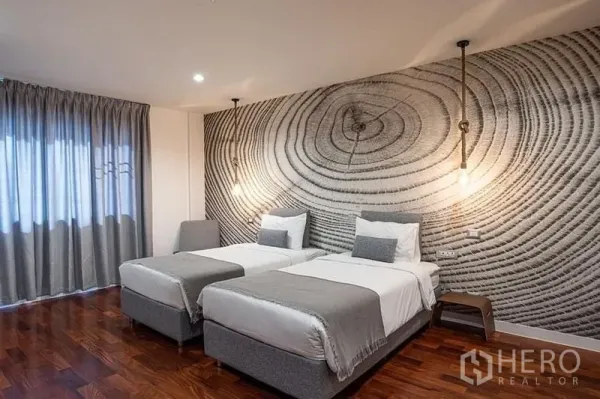 คอนโด ให้เช่าในPathum Wan, Bangkok - ห้องนอนที่สอง เตียงเดี่ยวสองเตียง ผนังลายวงปีไม้ โคมไฟห้อย และพื้นไม้โทนอุ่น