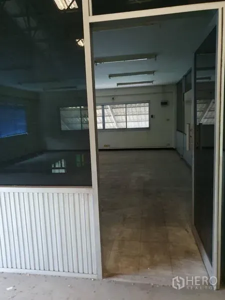 Factory for rent in Samut Prakan - Interior of the upper office showing tiled flooring, fluorescent lighting and wide windows.