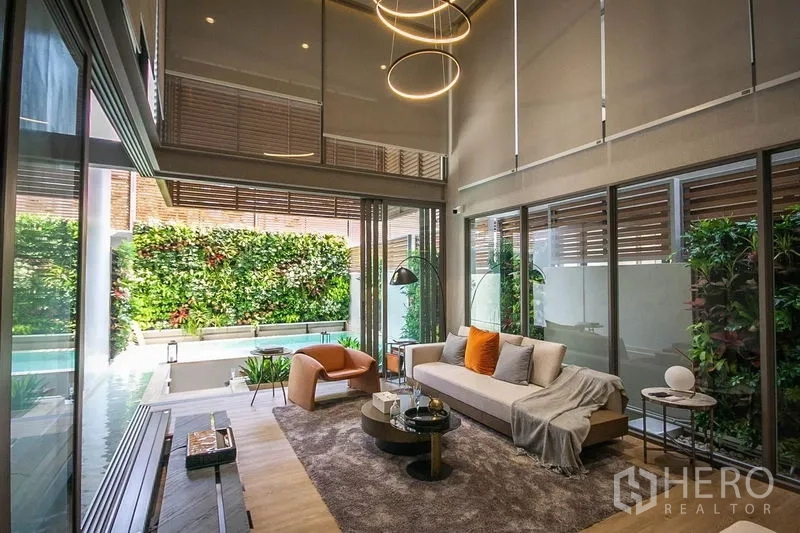 联排别墅 出售在Lat Phrao, Bangkok - 挑高客厅配落地窗，连接私家泳池与绿植立面