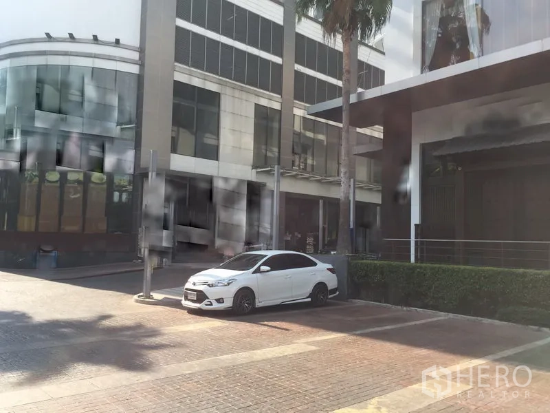 零售空间 出租在Khlong Toei, Bangkok - 现代商业综合体外观，带停车位、棕榈树与玻璃立面，临近轨道交通。