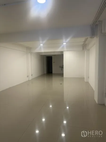 零售空间 出租 - 明亮的开放式零售空间，亮面瓷砖地面、白色墙面与顶灯。