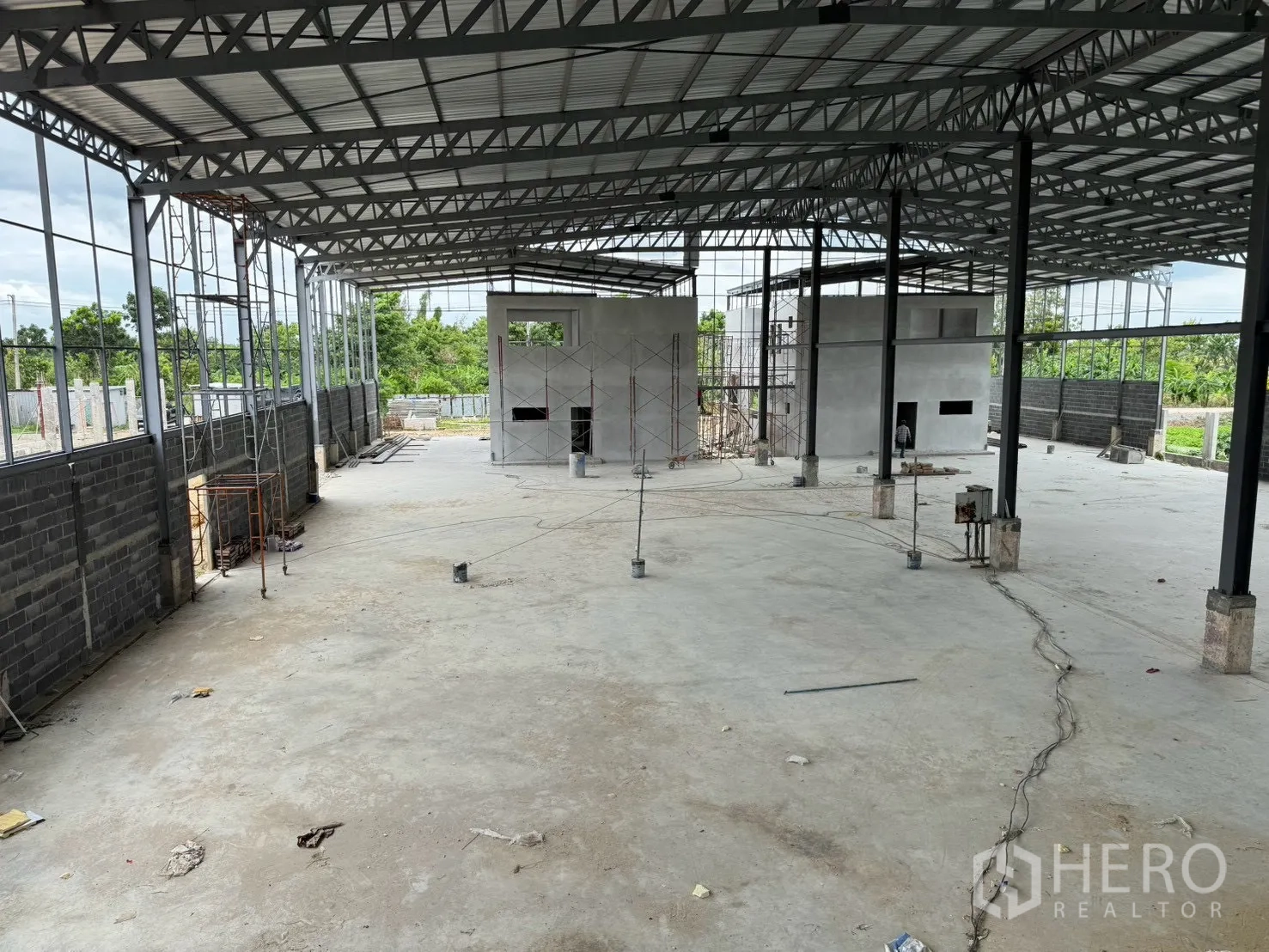 Factory for rent in Phutthamonthon, Nakhon Pathom - Spacious factory hall under steel trusses with open concrete floor and scaffolding.