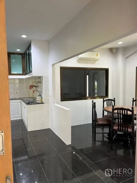 独立式住宅 出租在Samut Prakan - 餐区毗邻厨房，四人餐桌与壁挂空调。