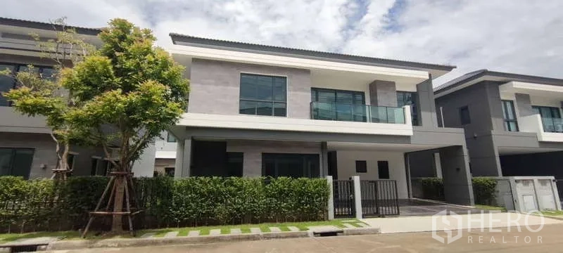 Detached House for rent in Bang Phli, Samut Prakan - Modern two-storey detached house exterior with balcony, carport and trimmed hedge fence.