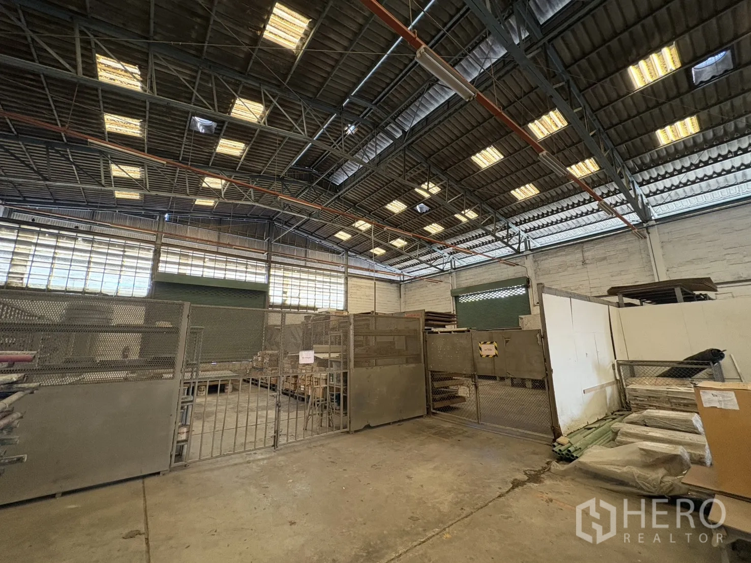 Factory for sale in Khlong Toei, Bangkok - Mesh-fenced secure storage area beside a green roller door