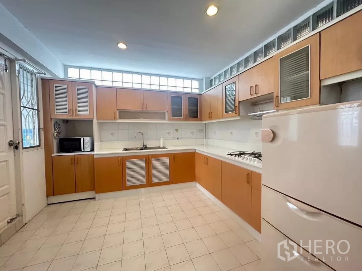 Detached House for rent in Suan Luang, Bangkok - Main kitchen with wood cabinetry, gas hob, and refrigerator.