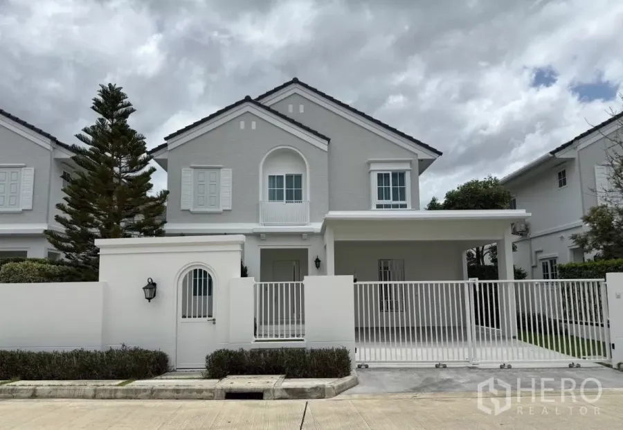 Detached House for rent or sale in Bang Phli, Samut Prakan - Two-storey white detached house with gated driveway and covered carport at Bangna KM.15 estate.