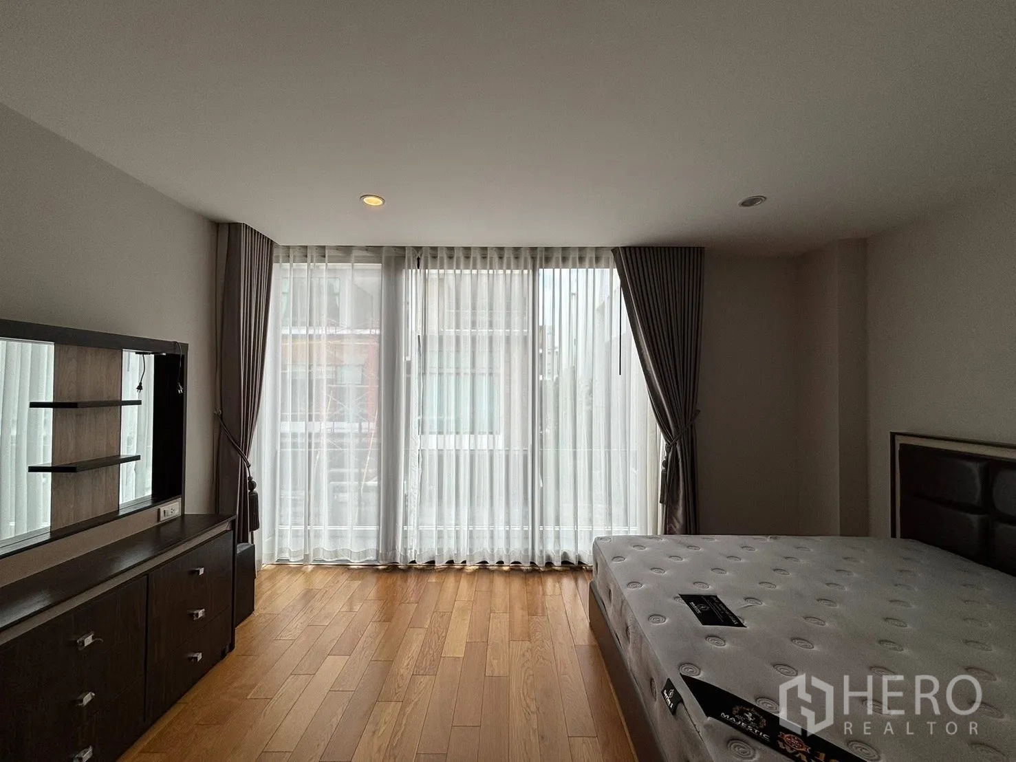 Townhouse for rent in Saphan Sung, Bangkok - Bedroom corner with large windows, sheer curtains, and a bed.