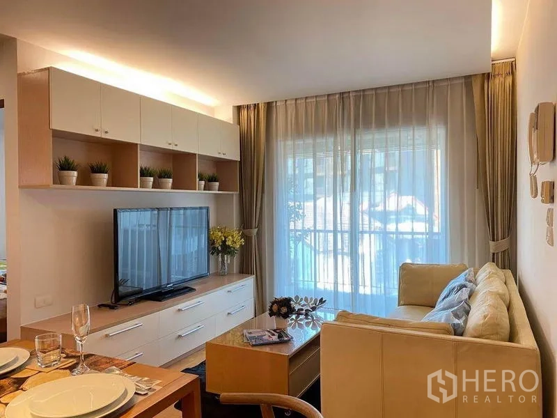 公寓 出租或出售在Phra Khanong, Bangkok - 客厅设沙发和电视柜，落地推拉门通向阳台。