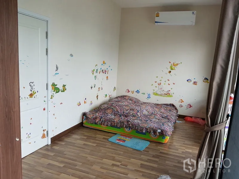 Detached House for sale in Samut Prakan - Children’s bedroom with floor mattress, playful wall stickers and wood flooring.
