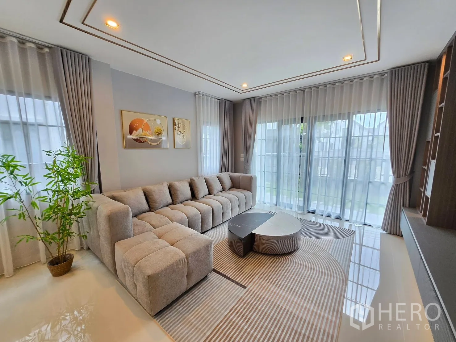 Detached House for rent in Bang Phli, Samut Prakan - Living area with floor-to-ceiling curtains, corner sofa, and designer coffee table.