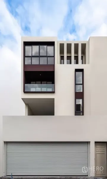 带办公室的家 出售在Phra Khanong, Bangkok - 现代多层居家办公楼立面，大窗、阳台与卷闸车库门。