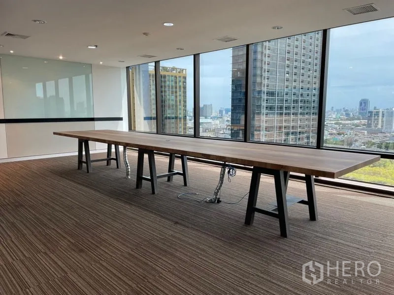 Office Space for rent - High-floor boardroom with a long meeting table and floor-to-ceiling windows overlooking the Bangkok skyline.