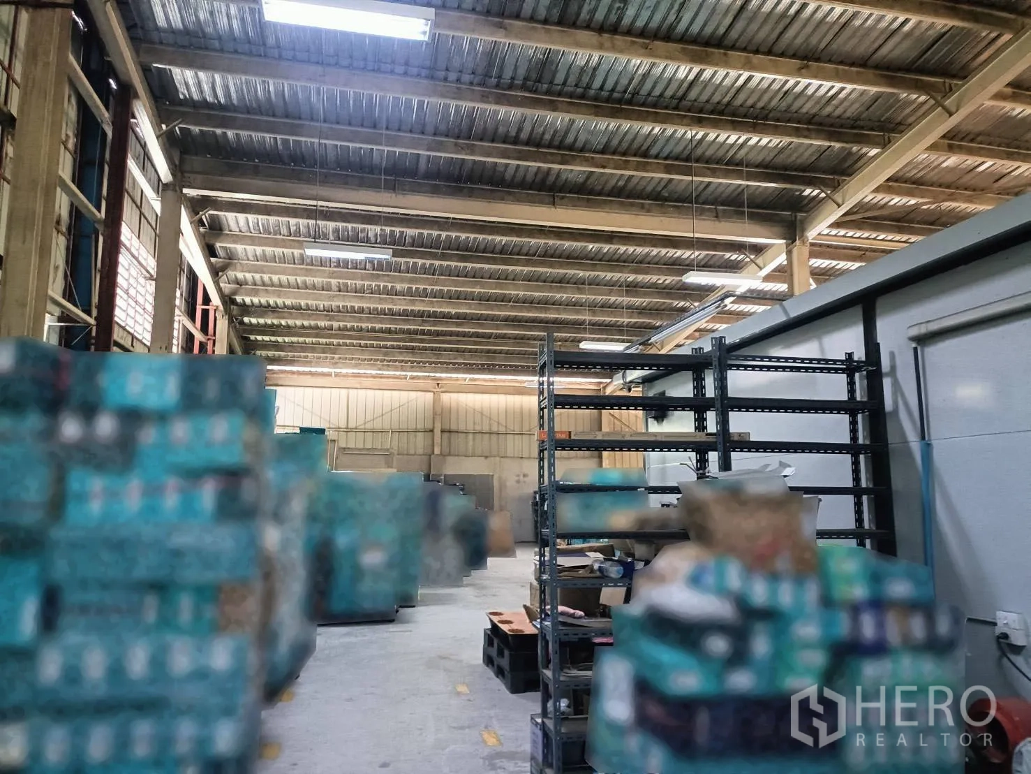 Warehouse for rent in Lam Luk Ka, Pathum Thani - Aisle inside the warehouse with steel shelving and pallets under bright lighting.